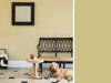 Little Greene - Oak Apple 63 op muur met een zwarte houtenbankje ervoor