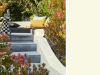 Little Greene - White Lead 74 dans un jardin verdoyant avec un canapé d'extérieur sur un petit muret en béton